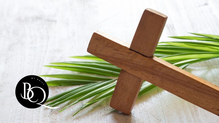 Palm branch next to a cross on a wooden table